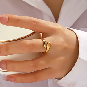 Minimalist golden geometric teardrop open ring worn by model holding a white cup