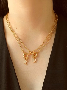 Close-up of double layer gold paperclip chain necklace with zircon K and R pendants