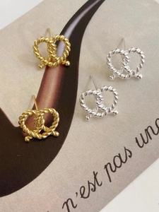 Detailed macro view of twisted silver knot earrings in both gold and silver finishes
