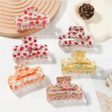 Close-up of 6 transparent hair claws with vibrant fruit prints on a minimal background