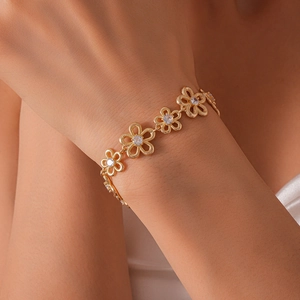 Macro detail of gold flower bracelet links featuring sparkling central zircon accents
