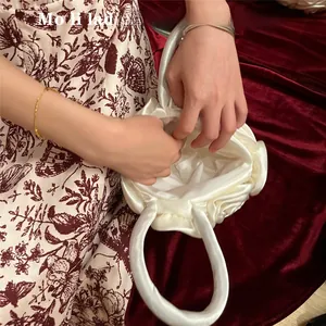 Detail view of the white satin rose petals and interior lining of the handmade evening bag