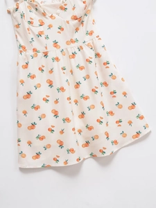 Détail du tissu léger avec imprimé d'oranges et de feuilles vertes sur la robe d'été