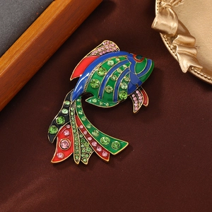 Colorful fish brooch with enamel finish and sparkling crystals on silk background