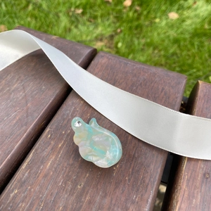 Gros plan sur la barrette aile en acétate bleu et blanc avec strass sur banc