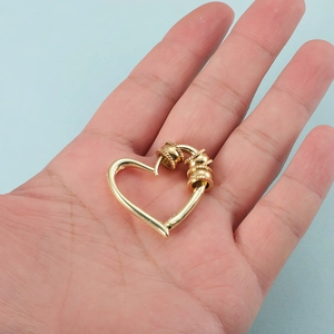 Golden heart-shaped spring clasp for DIY jewelry making shown held in hand