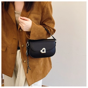 Detail of black matte shoulder bag with silver heart-shaped lock and woven cord