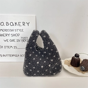 Gros plan sur le sac à main en peluche gris foncé à pois et sa doublure à carreaux