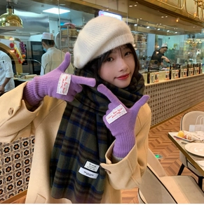 Winter outfit detail featuring purple knit gloves and white beret in a cozy cafe setting
