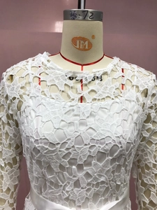 Detailed view of floral lace pattern and hollow embroidery on a white dress sleeve