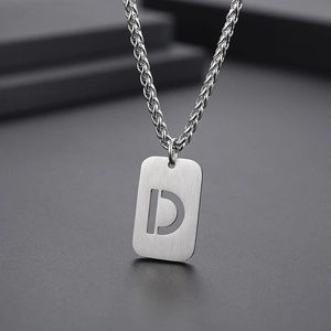 Gros plan d'un pendentif lettre D argenté brossé avec une chaîne maille torsadée