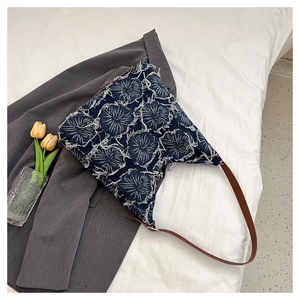 Detail of blue denim tote bag with 3D white fringe circles and brown leather strap