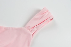 Détail de la robe rose montrant la texture froncée du tissu et la bretelle délicate