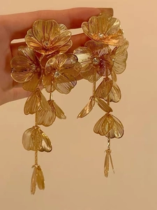 Macro shot of gold bridal flower earrings with long tassels and intricate metal petals