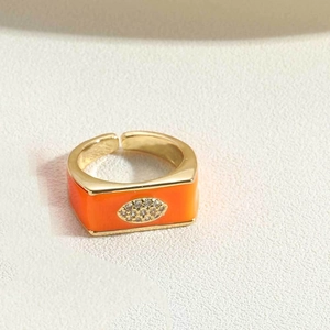 Detailed view of the gold open ring with orange enamel and sparkling crystal accents
