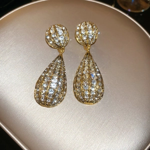 Close-up of teardrop earrings with gold plating and sparkling crystals on a tray