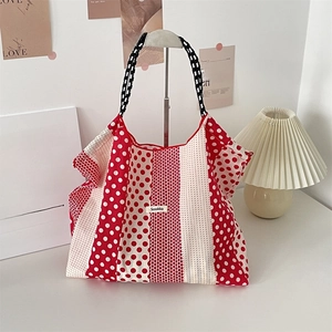 Detail of red and white polka dot canvas tote bag with black checkered shoulder straps