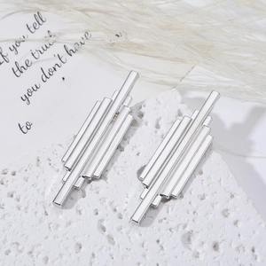 Minimalist long silver tassel geometric drop earrings displayed on a white textured stone