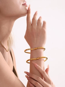 Detailed view of irregular wavy 18k gold plated stainless steel heart bracelets on wrist