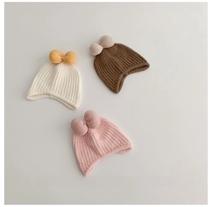 Detailed texture of thick ribbed knit baby hats with large bows in white, pink, and brown