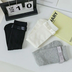 Detailed view of ribbed mid-calf socks with silk bows in black, white and grey colors
