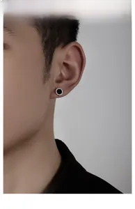 Close-up of men's round stud earring with black inlay and pavé zircon stones on ear