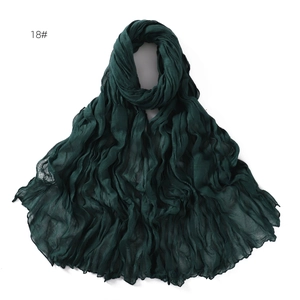 Detail shot of a dark green breathable cotton scarf featuring a unique twisted crinkle texture
