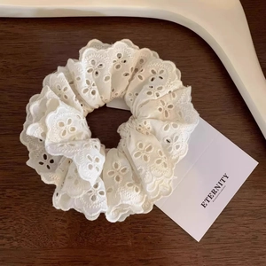 Chouchou vintage en dentelle blanche brodée sur un fond élégant en bois brun