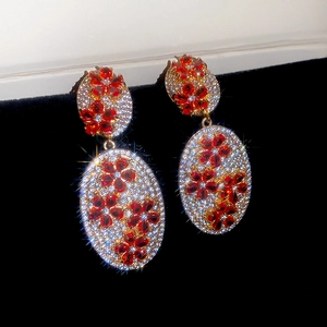 Detail view of vintage gold earrings with zircon flowers on black velvet display