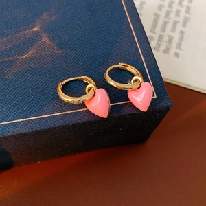 Close-up of vintage gold hoop earrings with pink enamel heart charms on a book page