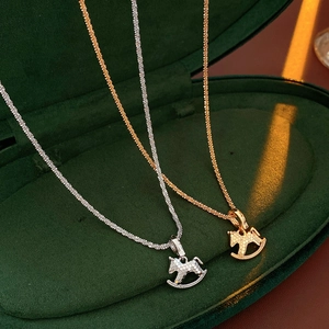 Dettaglio dei ciondoli a cavallo in oro e argento in una scatola di velluto