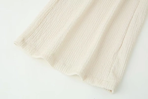 Close-up of cream white textured fabric showing fine pleats and premium stitching detail