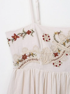 Detail view of ethnic floral embroidery and lace trim on beige sleeveless dress