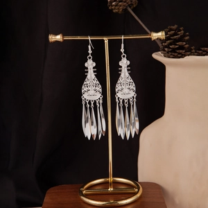 Detail of silver bohemian tassel earrings hanging on a display stand with vintage vibe