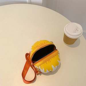 Overhead view of a yellow and white round crossbody bag with an open zipper on a table