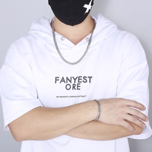 Close-up of silver Cuban link chain necklace and bracelet set on a streetwear model