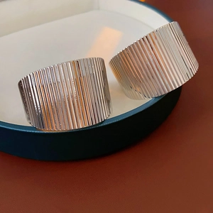 Detailed macro view of wide silver-finish metal cuff bracelets with textured vertical stripes