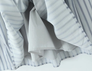 Detail view of the fine striped fabric hem and solid lining of the casual summer dress