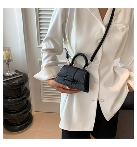 Mini black lychee leather bag with crossbody strap shown on white suit jacket