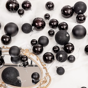 Gros plan de boules de Noël noires en finitions mate, brillante et pailletée sur velours
