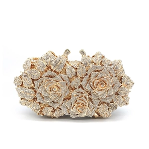 Detailed close-up of a luxury gold metal evening clutch featuring 3D crystal rose flowers
