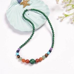 Close-up of colorful natural stone beaded necklace on a blue shell dish with flowers