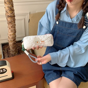 White quilted pouch with cute bear embroidery and blue strap, used as a makeup bag