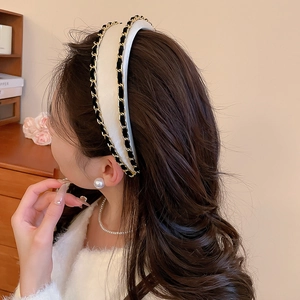 Detail of white fabric headband with black and gold chain trim for an elegant look