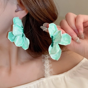 Gros plan sur les boucles d'oreilles fleurs vert menthe aux bords blancs brillants