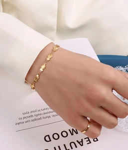 Close-up of golden fish link bracelet and minimalist ring on a female wrist