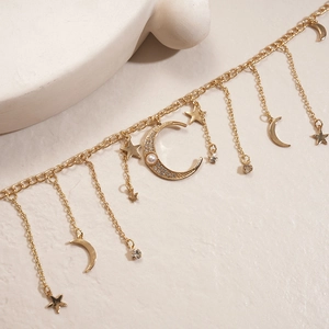 Détail d'un collier doré avec pendentifs étoile et lune, perles et strass scintillants