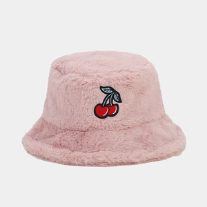 Detail of pink faux fur bucket hat featuring cute red cherry embroidery and soft texture