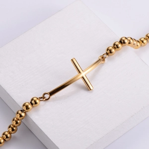 Minimalist gold plated titanium steel cross beaded bracelet for women on white background