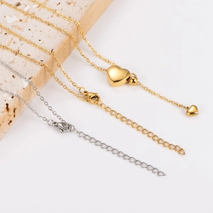 Gold and silver tassel heart necklaces with lobster clasps on a textured stone base